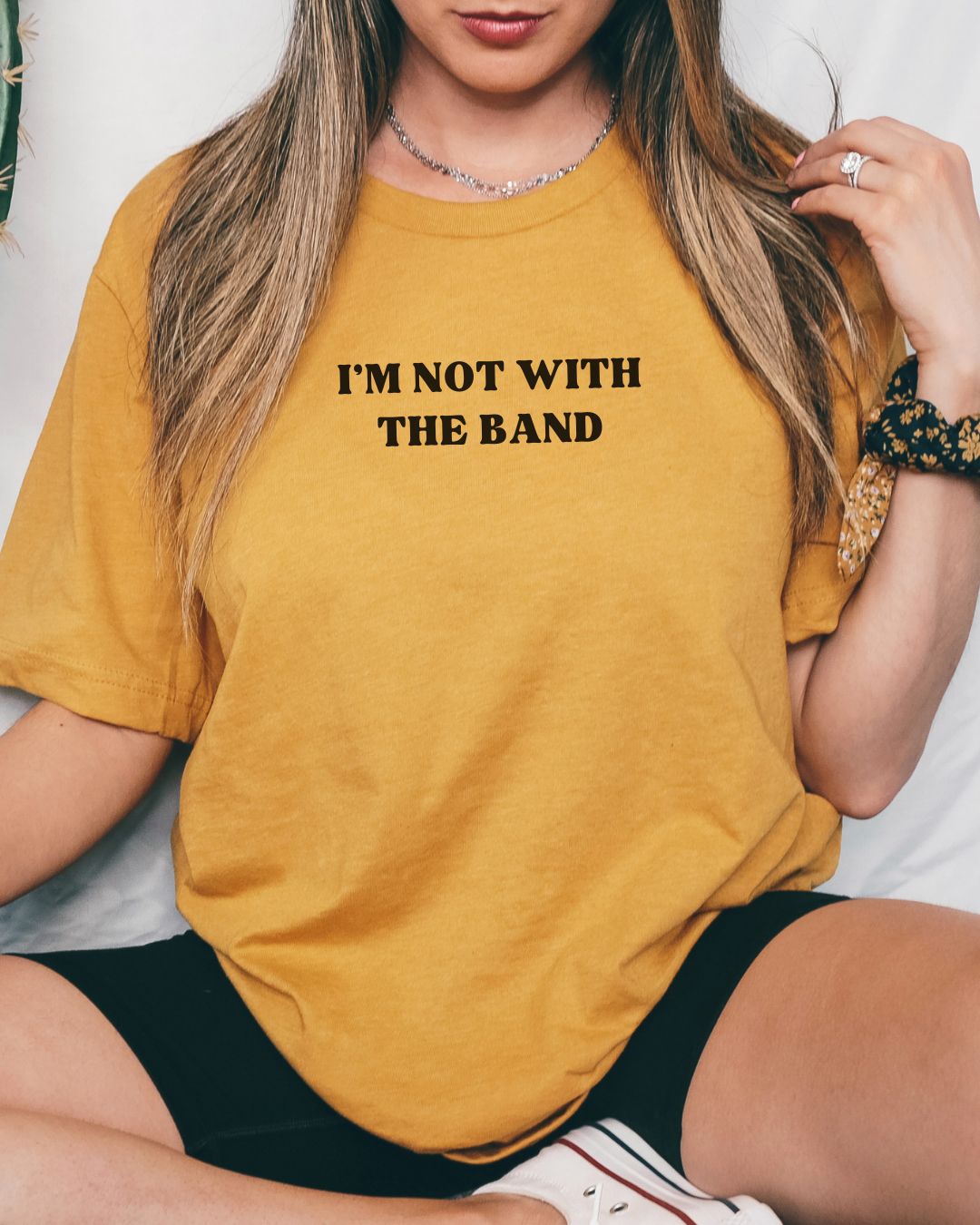 Person wearing a mustard yellow t-shirt with 'I'm not with the band' text.