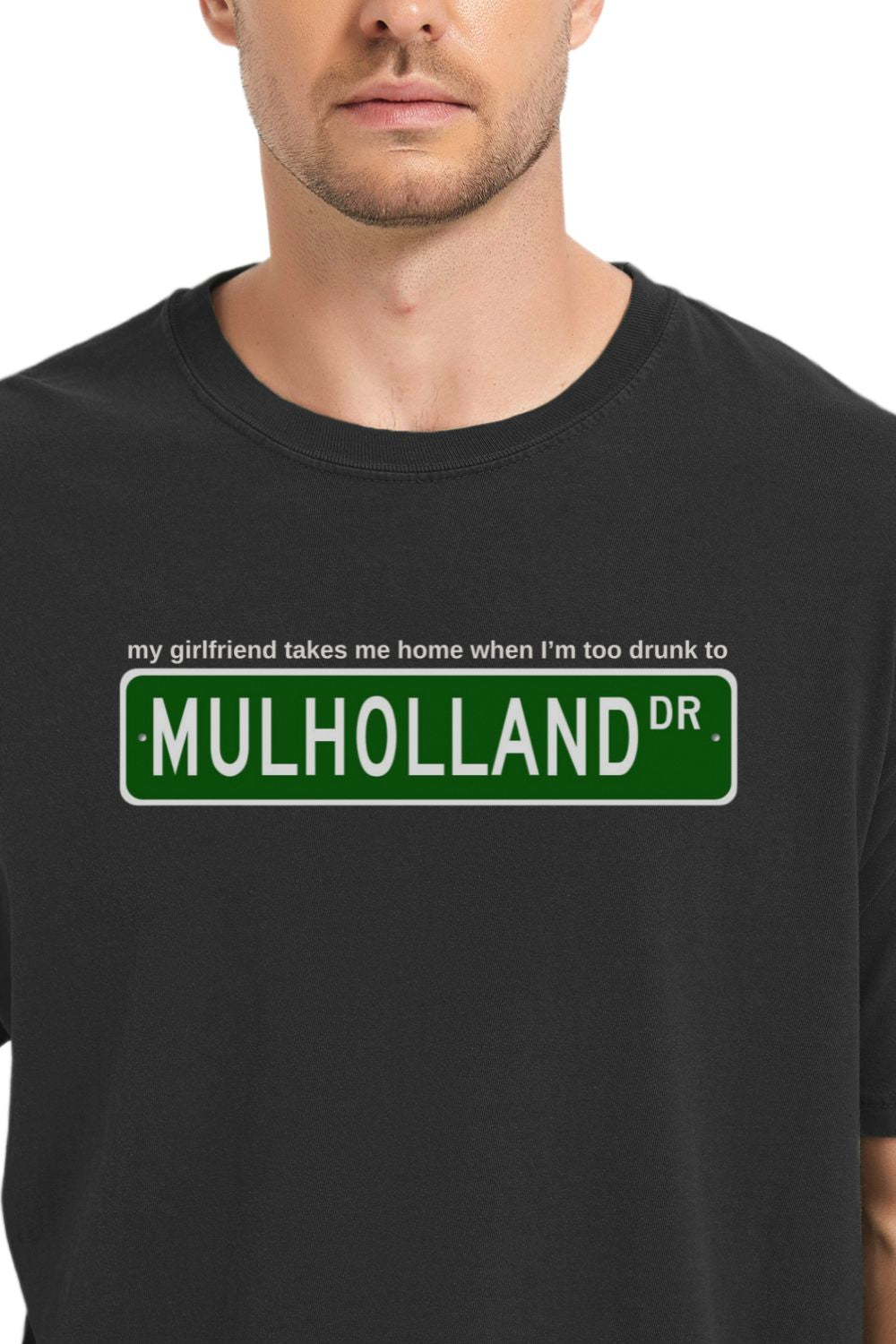 black t-shirt with Mulholland Drive street sign design on a white background, with blink 182 lyrics my girlfriend takes me home when I'm too drunk to drive, worn by a person