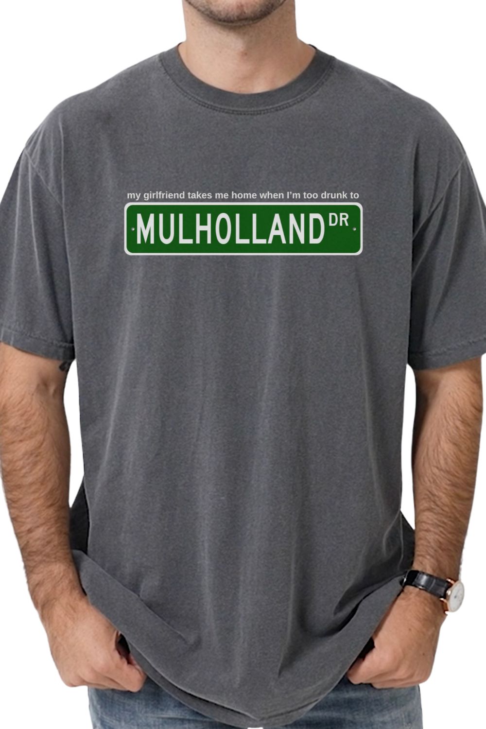 gray t-shirt with Mulholland Drive street sign design on a white background, with blink 182 lyrics my girlfriend takes me home when I'm too drunk to drive, worn by a person