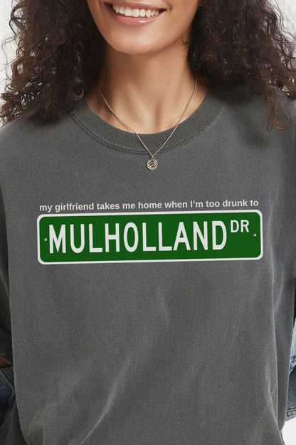 gray t-shirt with Mulholland Drive street sign design on a white background, with blink 182 lyrics my girlfriend takes me home when I'm too drunk to drive, worn by a person