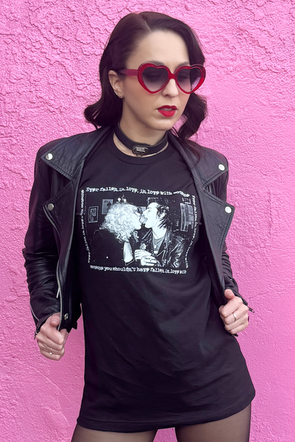 Person wearing a black 70s punk graphic t-shirt and leather jacket against a pink wall