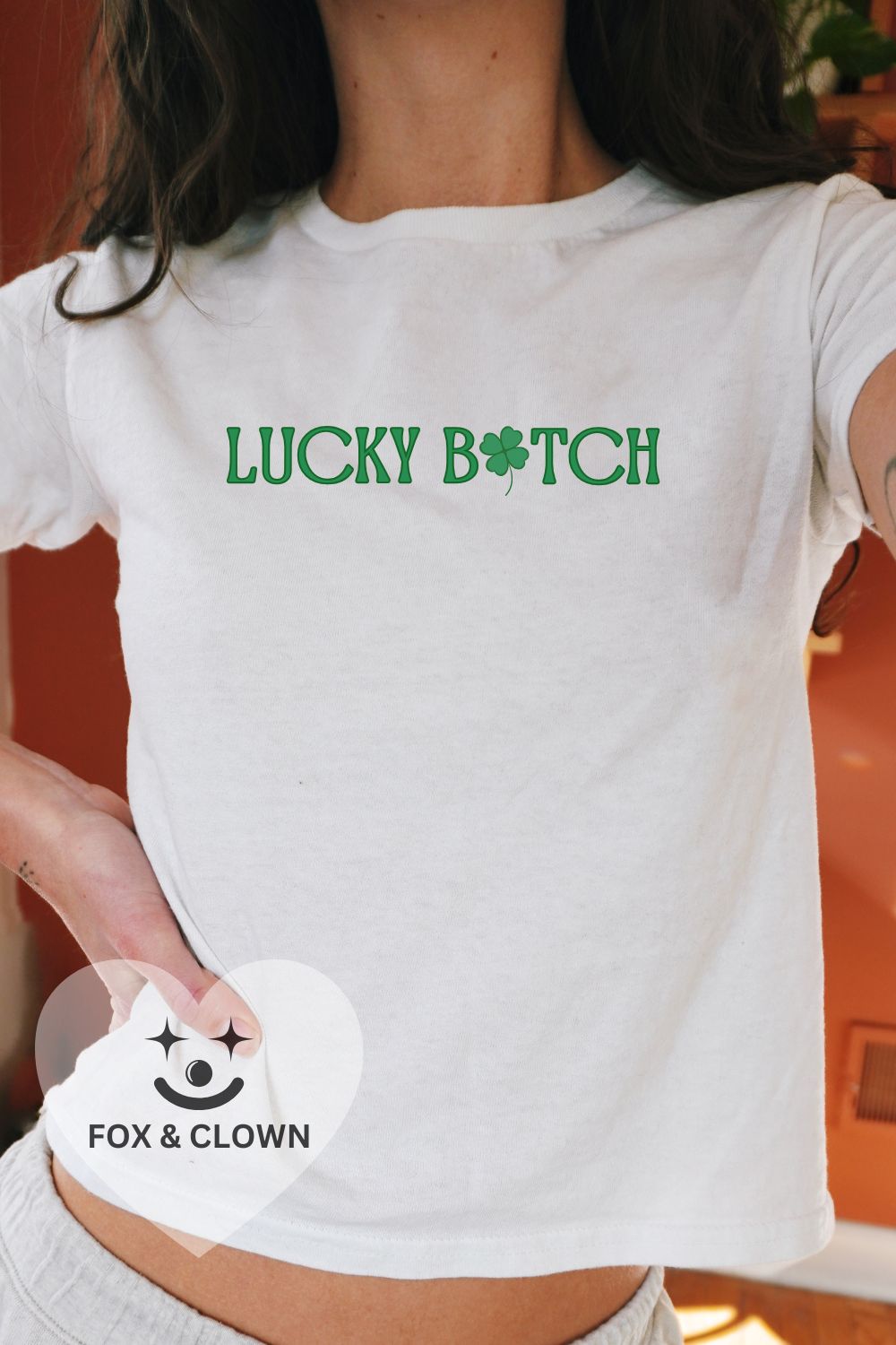 white st pattys day baby tee that says lukcy b*tch with a shamrock for the "I"