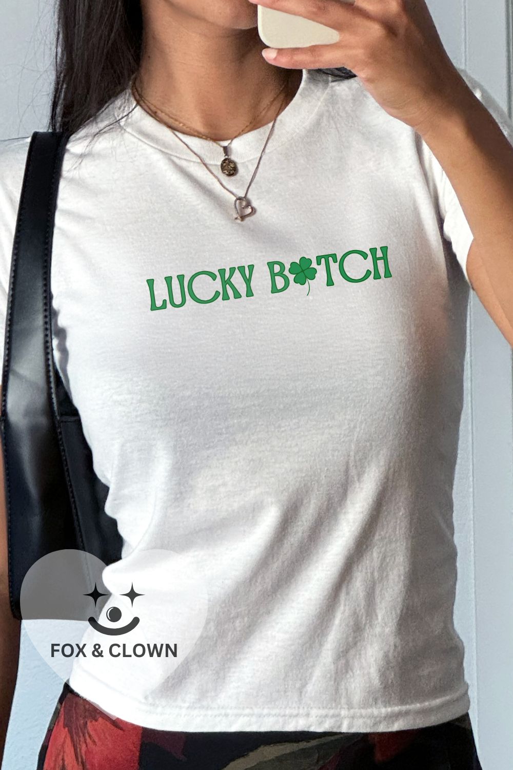 white baby tee that says lucky bitch with a shamrock for the letter "I"