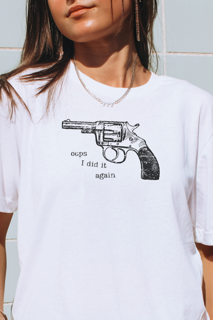 Person wearing a white t-shirt with a graphic of a revolver and text.