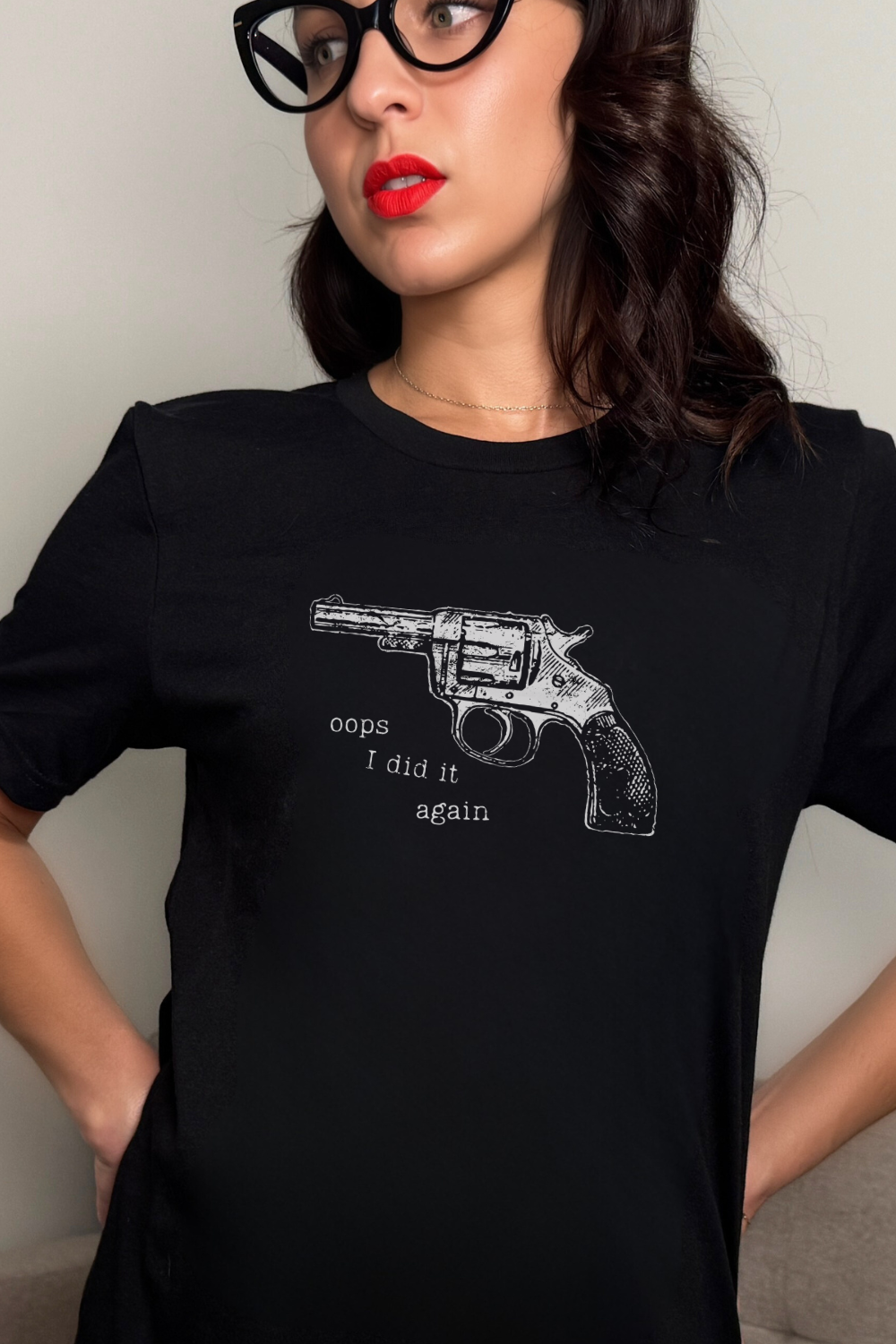 Person wearing a black t-shirt with a graphic of a revolver and text, against a plain background.